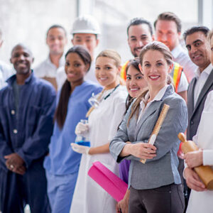 A multi-ethnic group of varied business professionals are standing together and are smiling while looking at the camera.